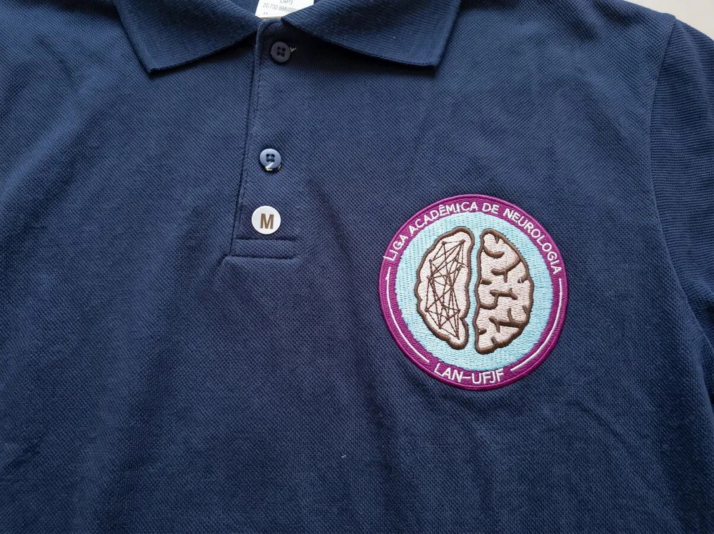Polo azul marinho com brasão de liga acadêmica bordado no peito