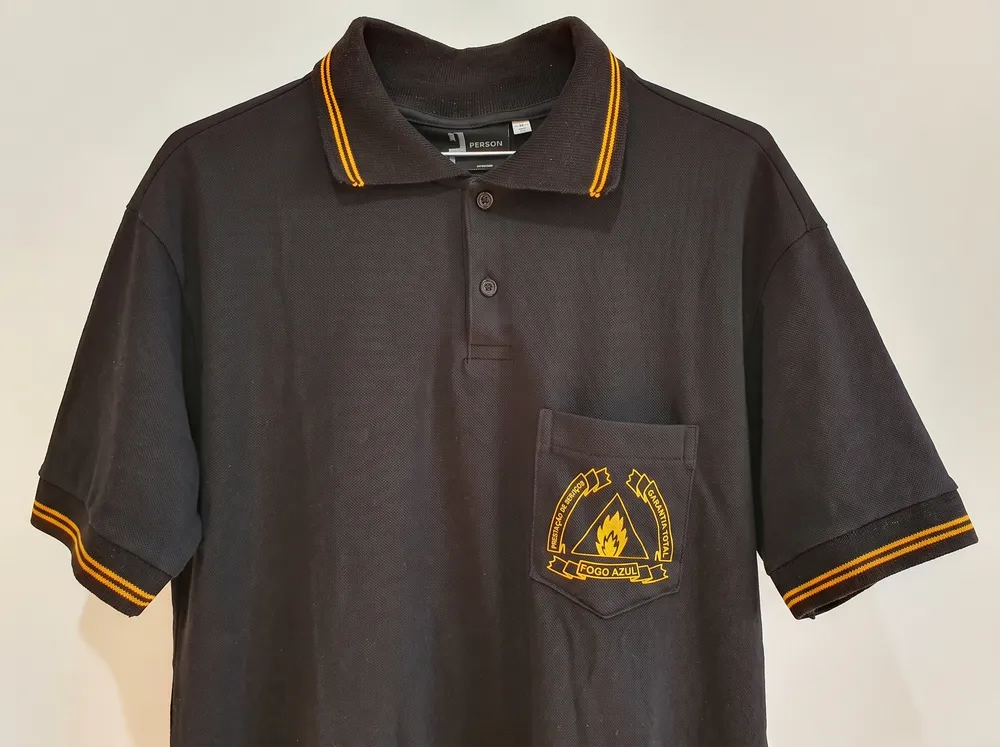 Polo preta com friso dourado nas mangas e emblema no bolso