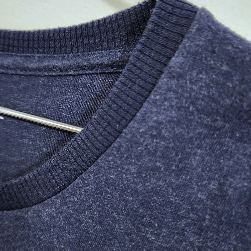 Detalhe da gola reforçada de camiseta azul mescla